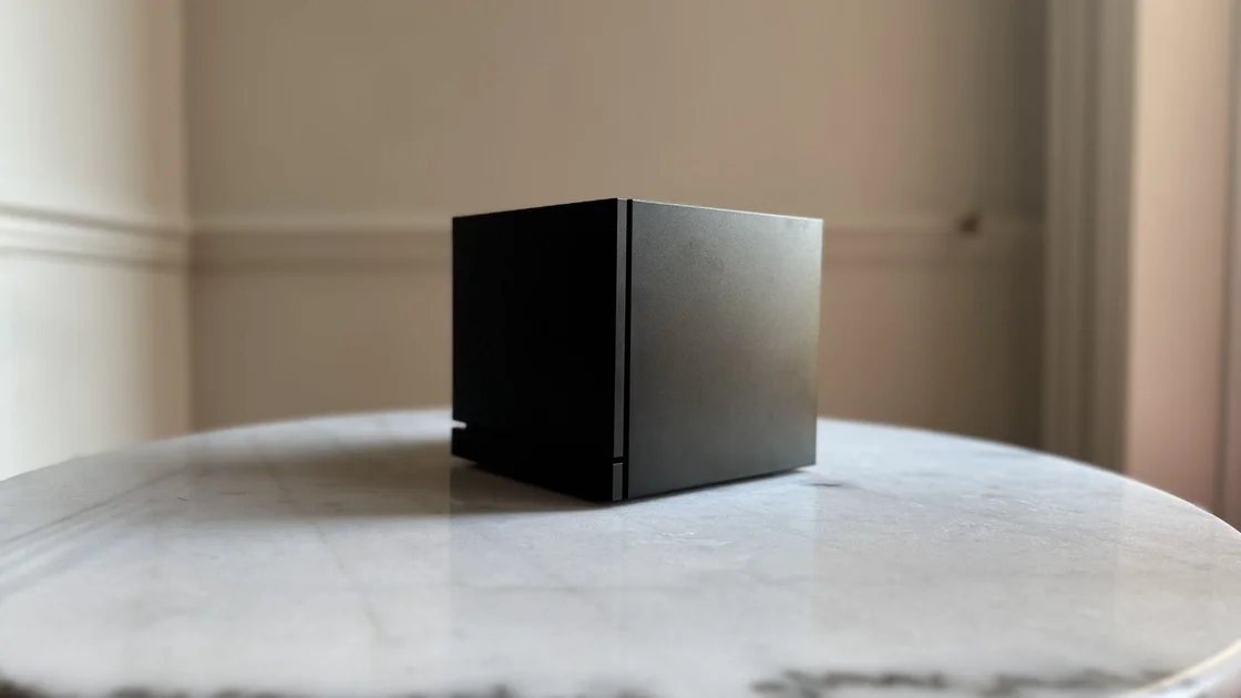 Steam Machine photograph showing the steam machine with black faceplate on a marble circular table in front of a grey/beige wall, from a diagonal angle