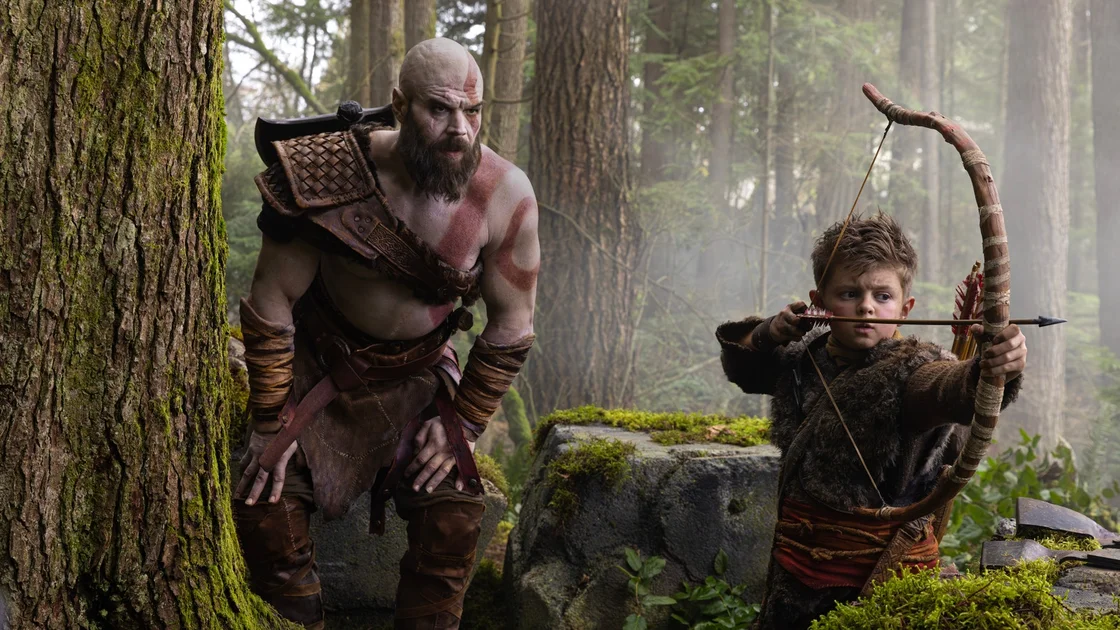 A still from the God of War TV series showing Kratos teaching Atreus, a young boy, how to hunt.
